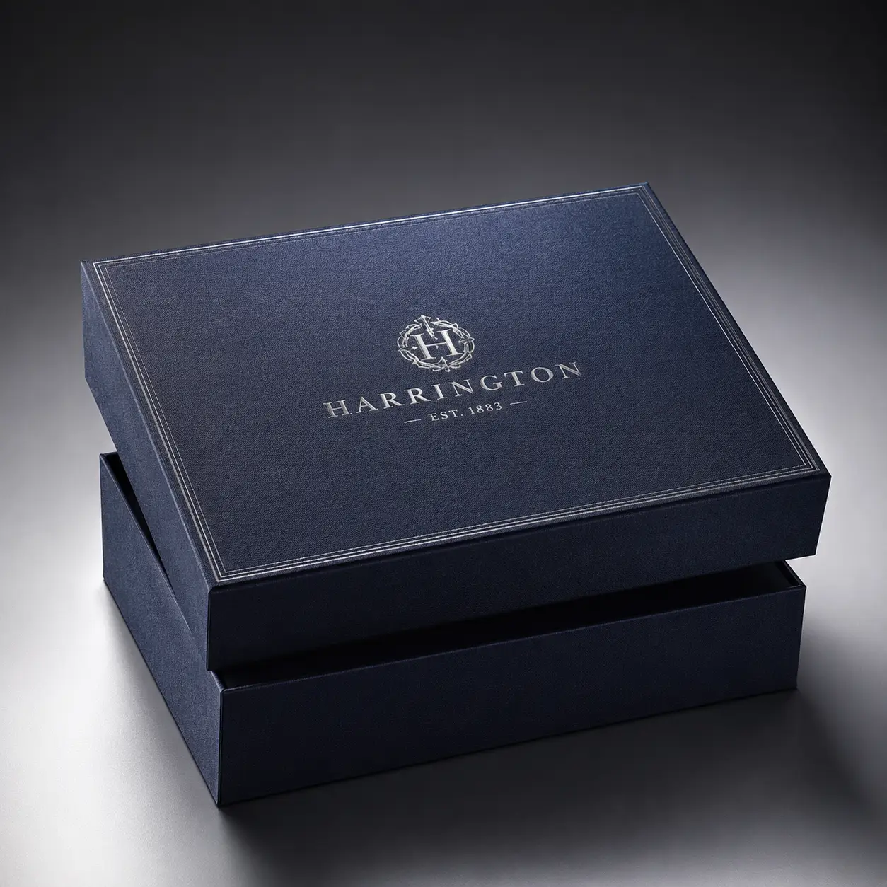 Navy blue luxury gift box with silver Harrington Est. 1883 embossed logo, elegant premium rigid packaging, dark moody studio shot