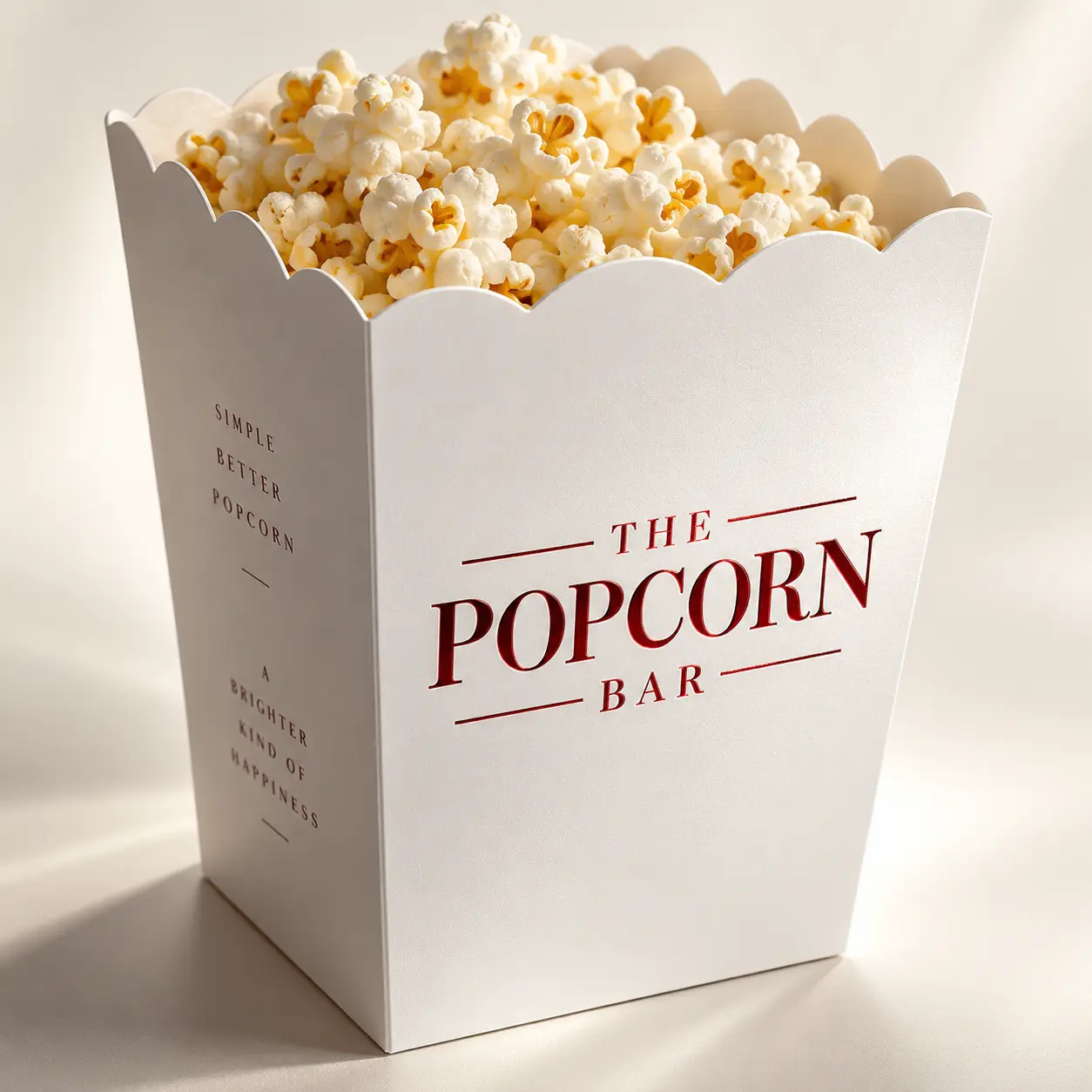 White popcorn box packaging design for The Popcorn Bar, filled with fresh buttered popcorn, clean minimal branding, scalloped edges