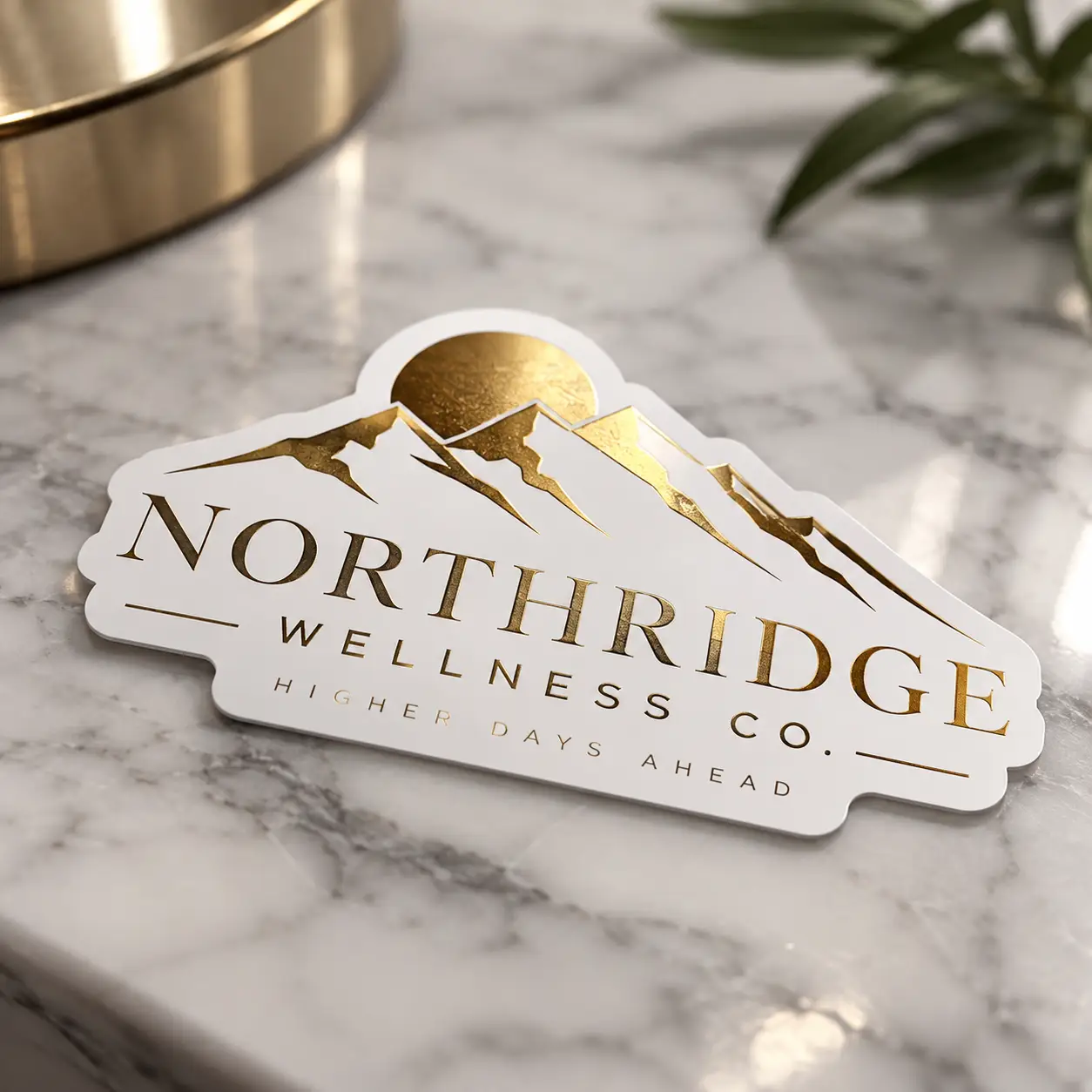 Gold foil die-cut sticker for Northridge Wellness Co on marble surface, white background with mountain logo, luxury custom sticker printing