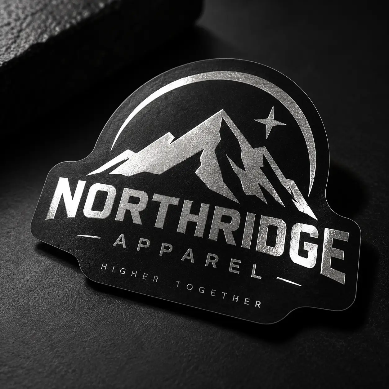 Black metallic sticker with silver foil Northridge Apparel logo featuring mountain peaks and star, Higher Together tagline