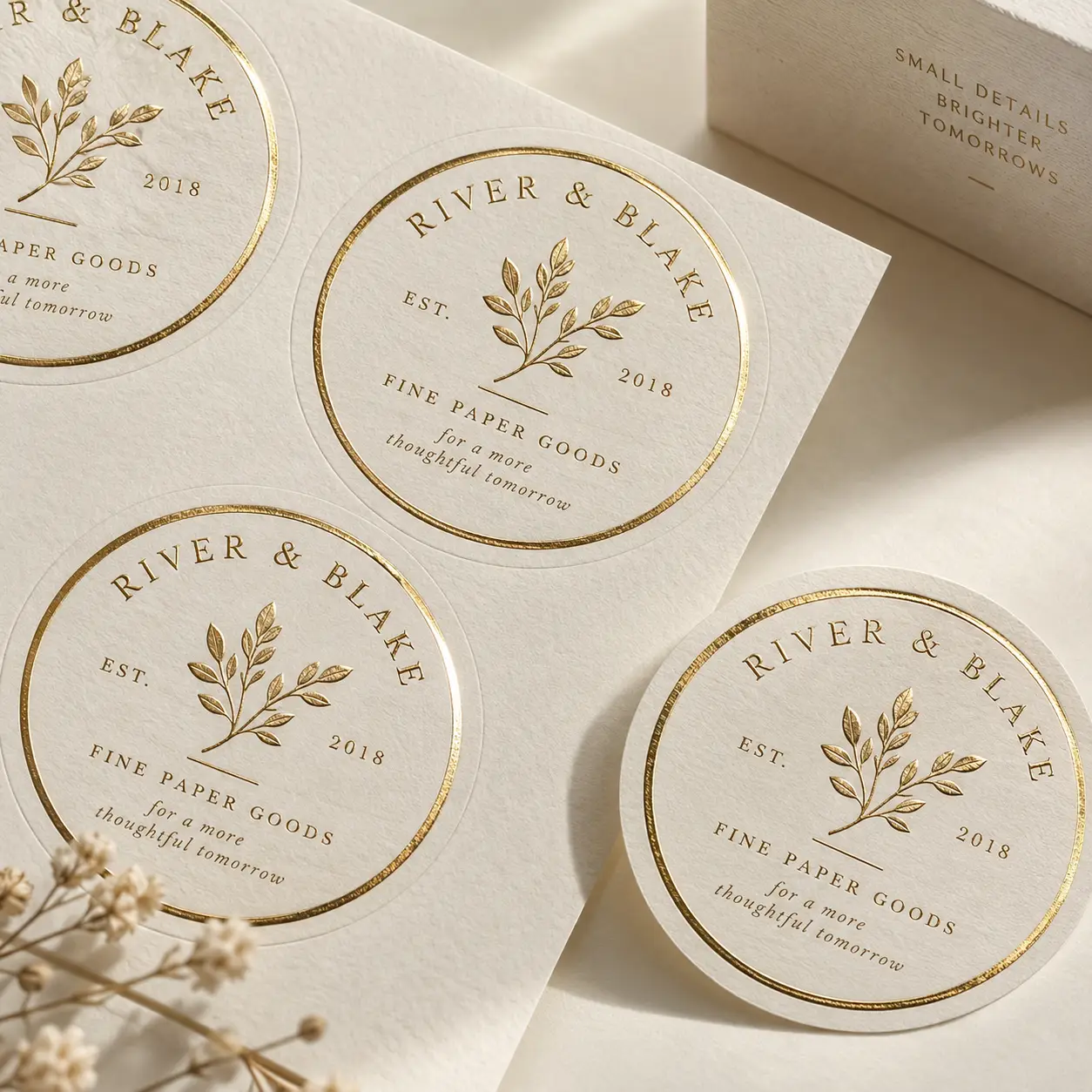 Gold foil round stickers for River & Blake Fine Paper Goods EST 2018 on cream textured paper with botanical leaf design