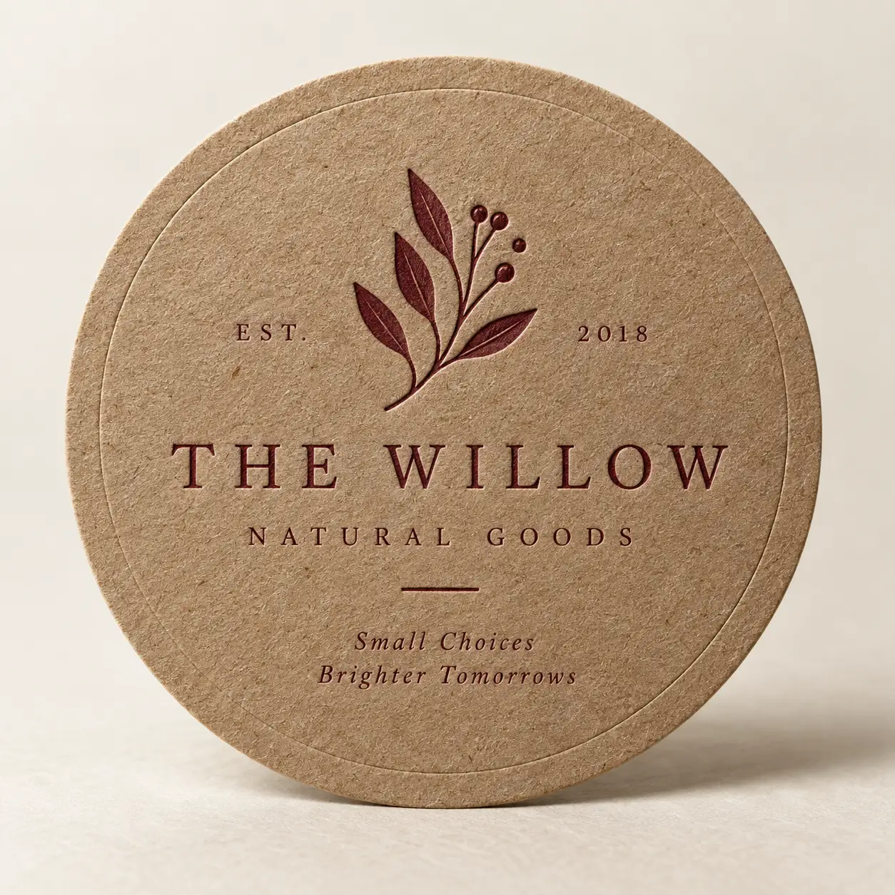Round kraft paper coaster with burgundy botanical logo for The Willow Natural Goods, EST. 2018, eco-friendly packaging design