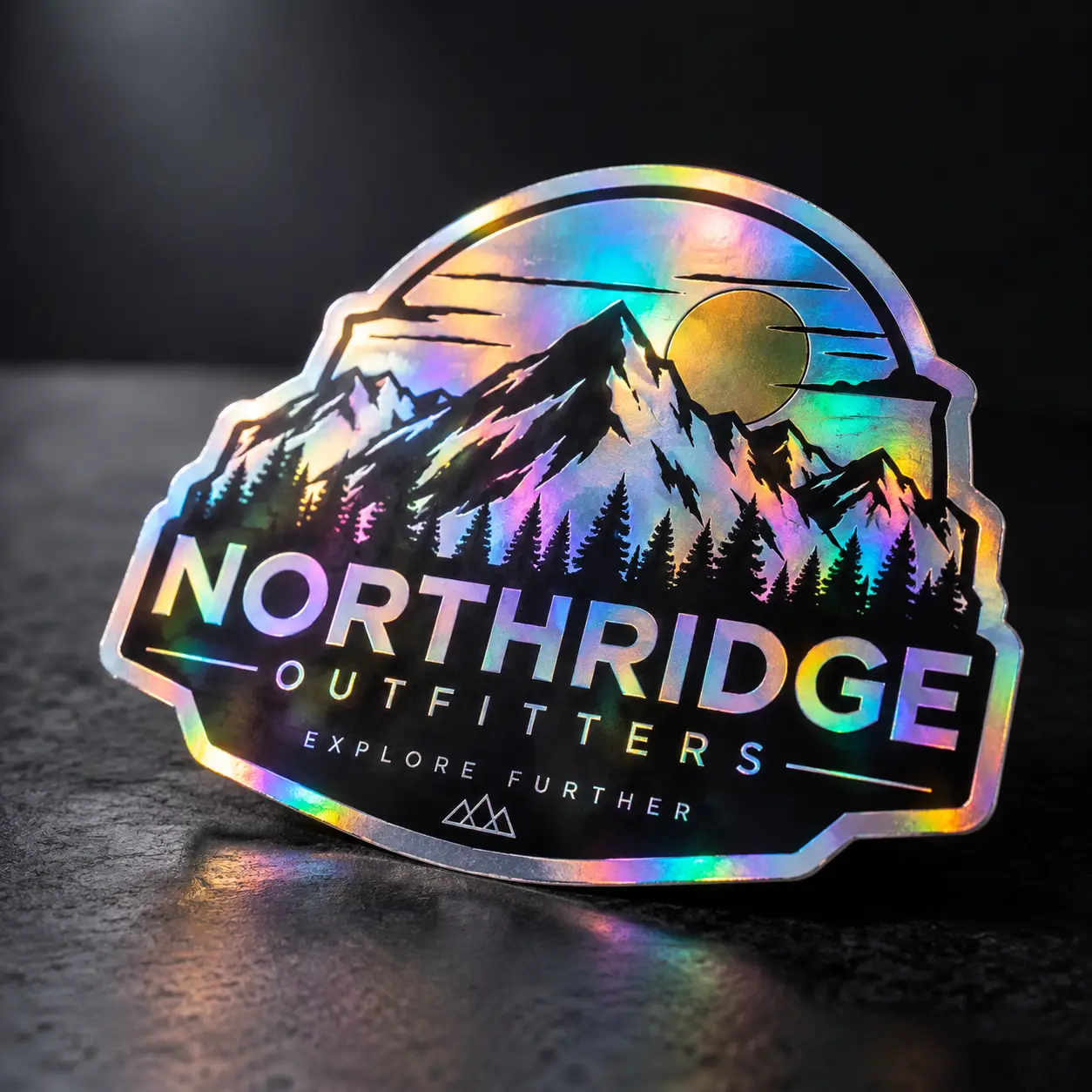 Holographic die-cut sticker for Northridge Outfitters featuring iridescent rainbow mountains, pine trees, and Explore Further tagline