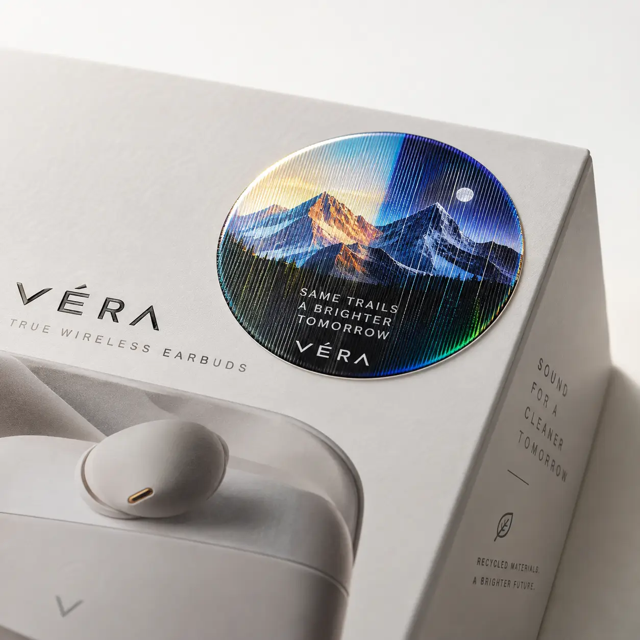 Véra True Wireless Earbuds premium white packaging with holographic mountain sticker and eco-friendly recycled materials branding