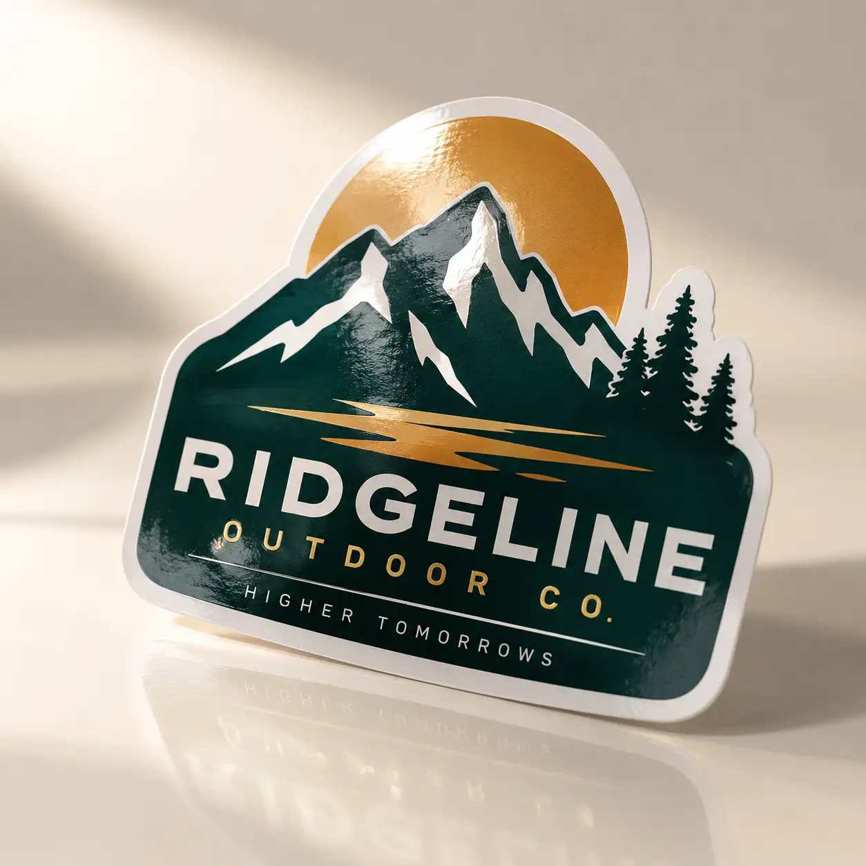 Die-cut sticker for Ridgeline Outdoor Co. featuring dark green mountains, gold sun, pine trees, white text on glossy finish