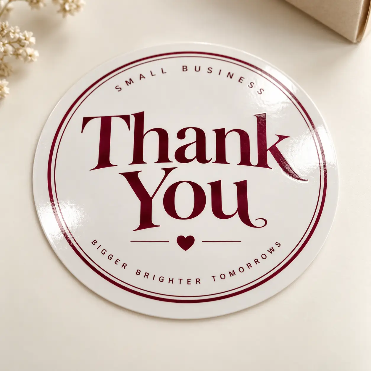 Glossy white round small business thank you sticker in burgundy text reading Bigger Brighter Tomorrows by The Packaging Masters