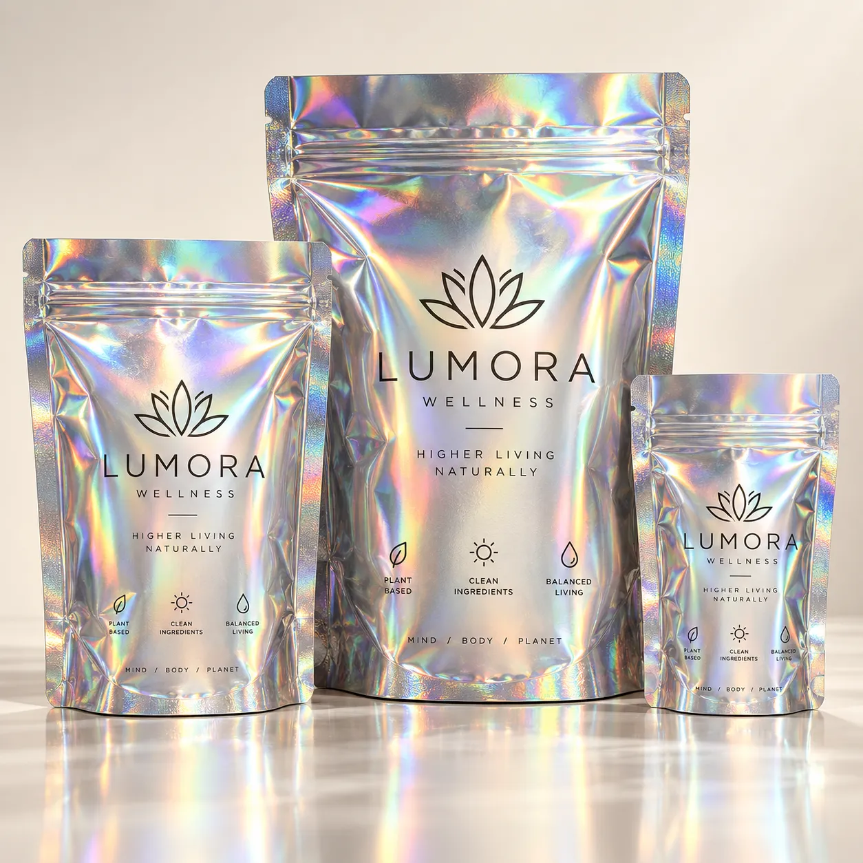 Three holographic silver mylar stand-up pouches for Lumora Wellness, custom wellness packaging in small, medium, large sizes