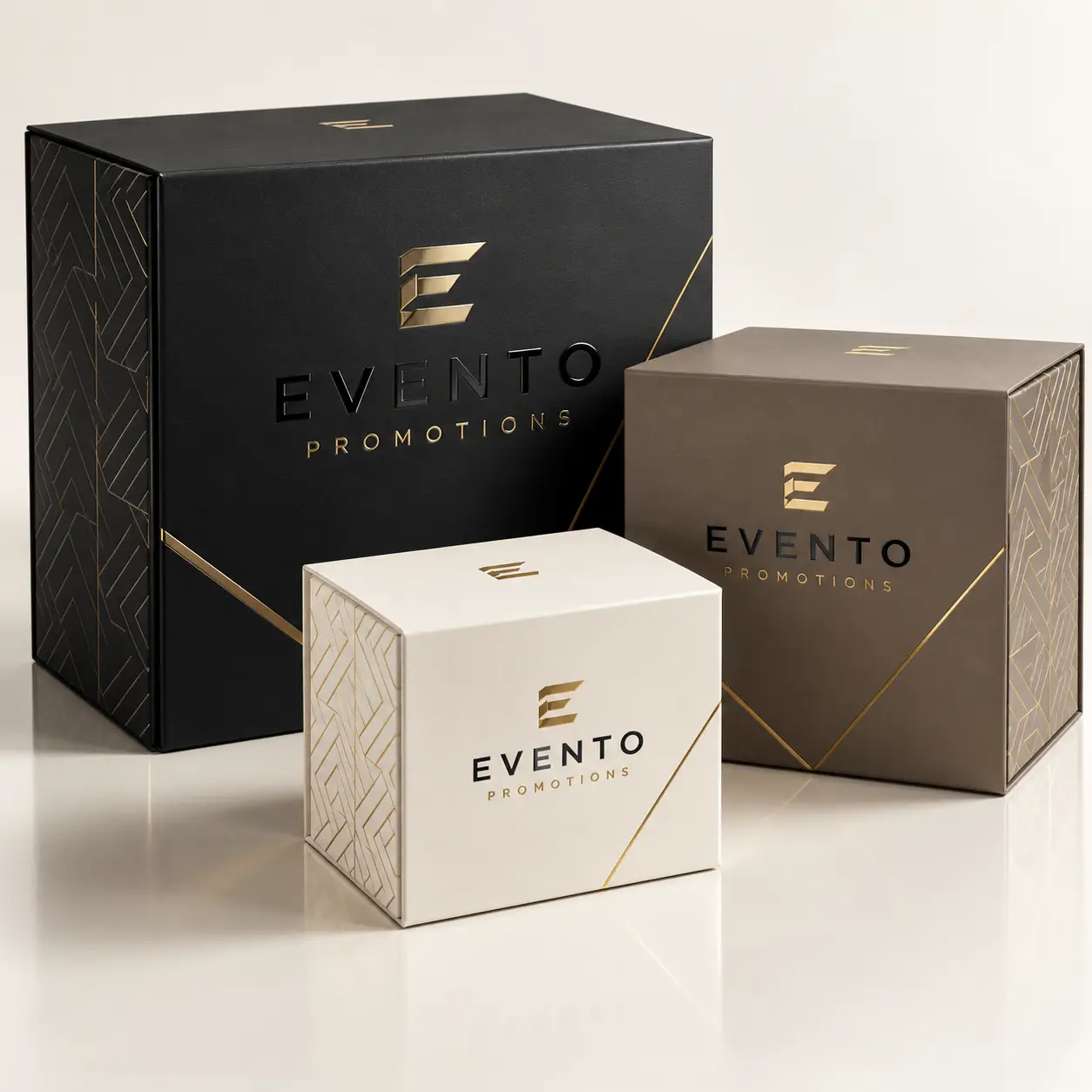 Three luxury Evento Promotions gift boxes in black, white, and taupe with gold foil logo and geometric patterns
